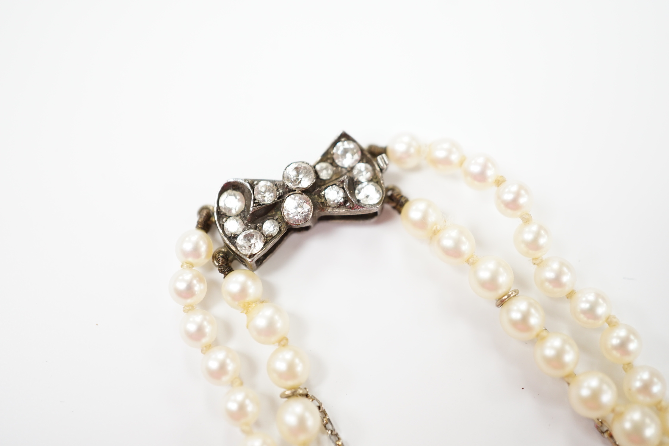 A double strand graduated cultured pearl necklace, with paste set white metal clasp, 44cm.